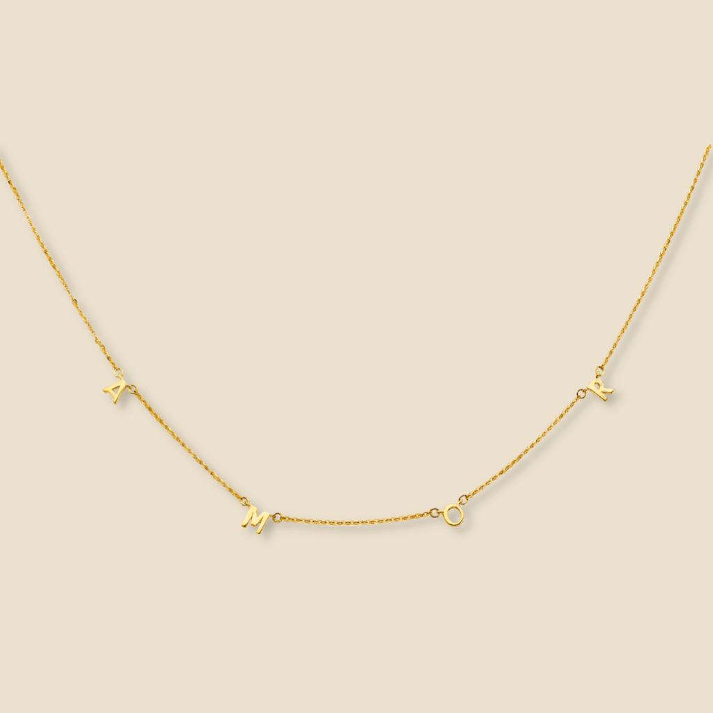 14K Gold AMOR Necklace displayed on a plain background, showcasing its delicate love letter design, polished gold finish, and adjustable 17'' + 1'' extender chain.