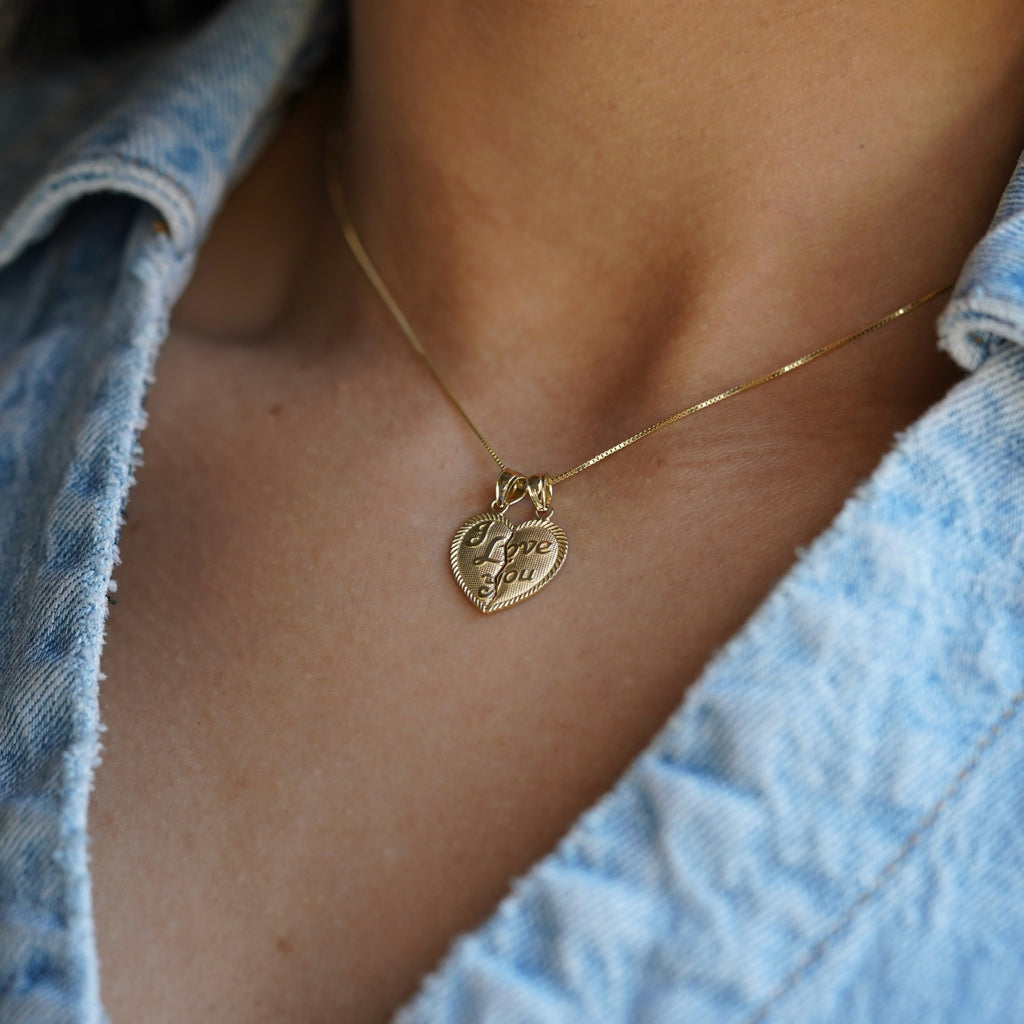 Close-up side angle of a model wearing the 14K Solid Gold 'I Love You' Breakable Heart Pendant, capturing the delicate breakable detail and shiny gold finish.