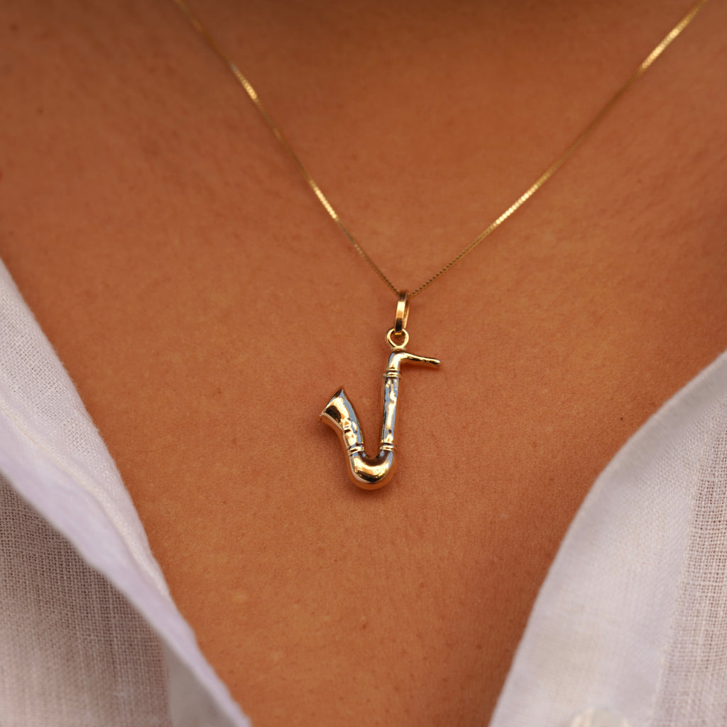 Model wearing the 14K Gold Saxophone Charm on a chain, showcasing its intricate musical instrument design and polished yellow gold finish.