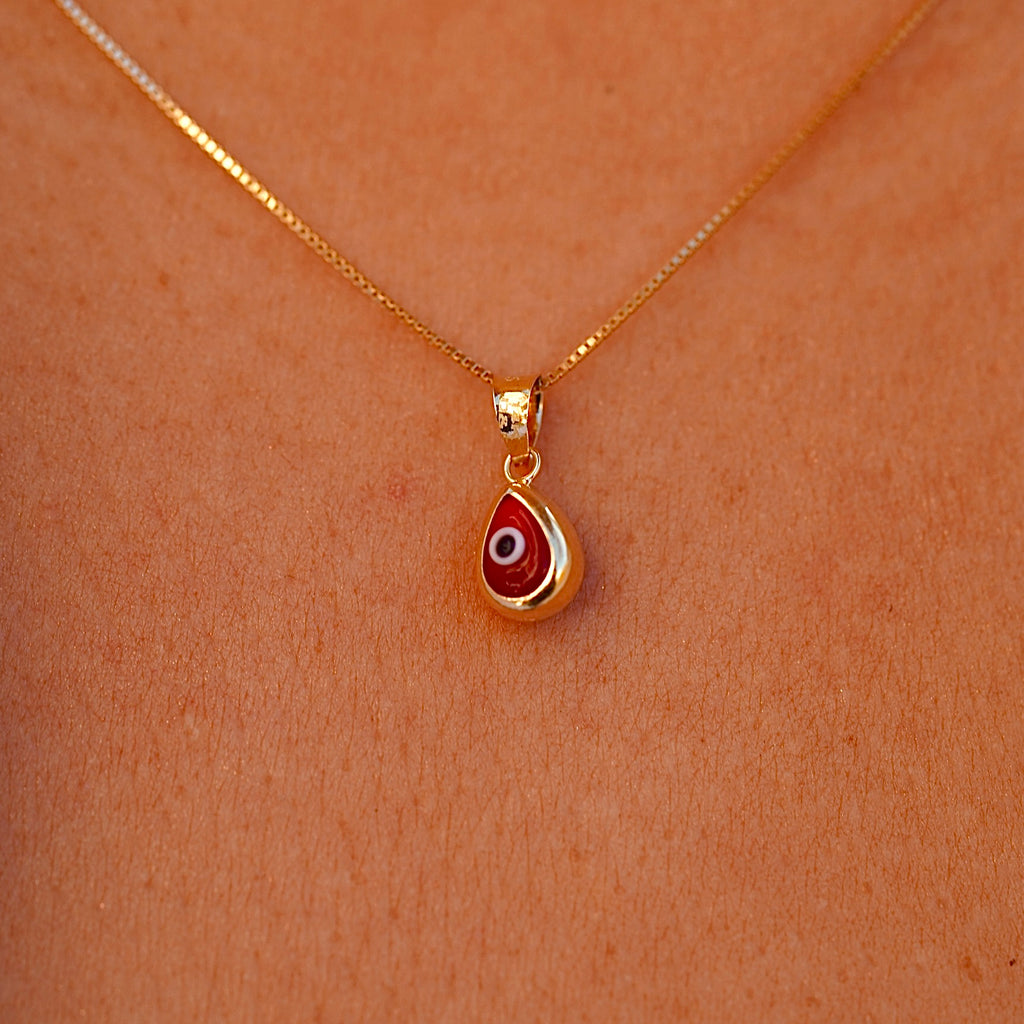A model wears the 14K Gold Tiny Tear Evil Eye Charm with the vibrant Red eye, adding a touch of protection and elegance to her necklace.