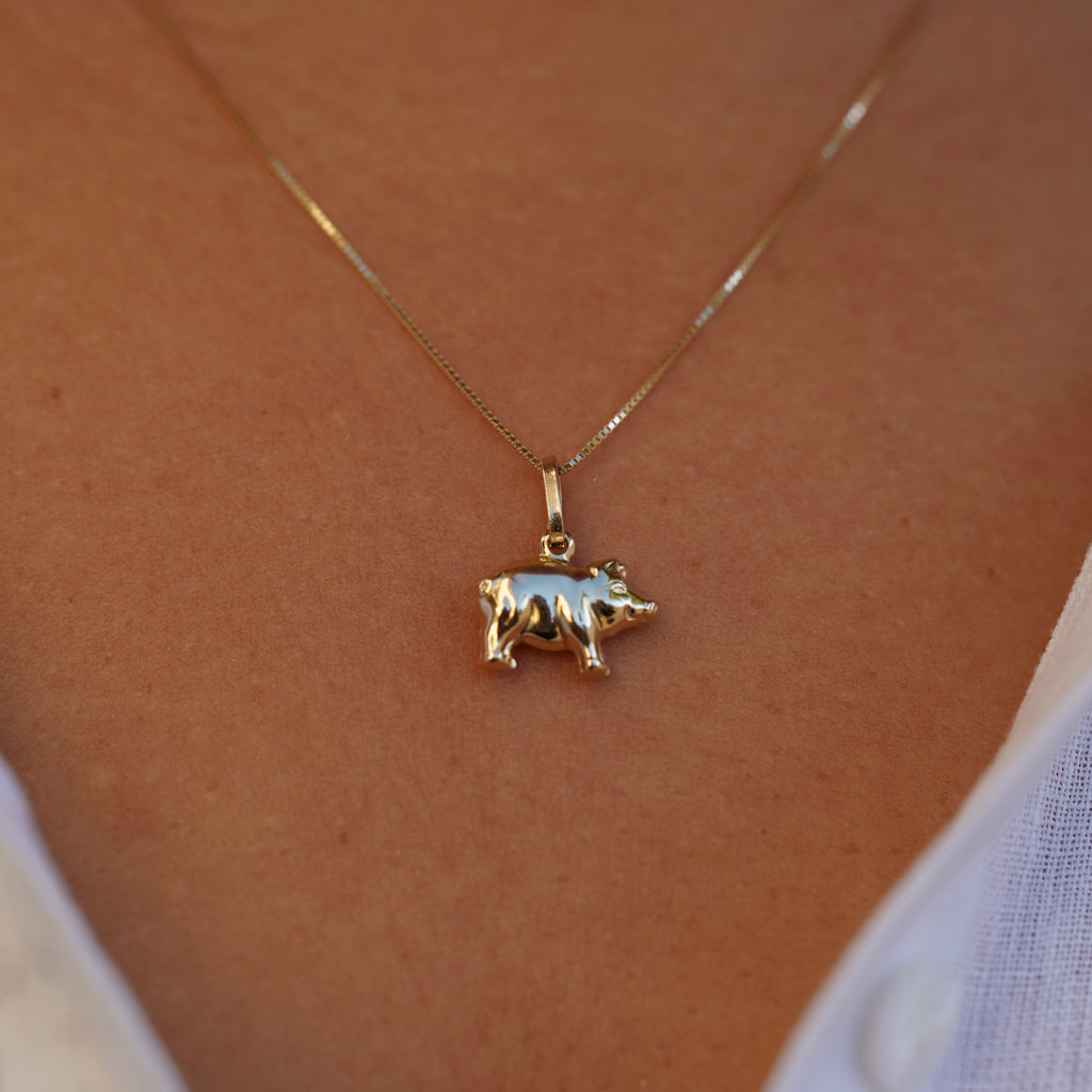 14K Solid Gold Pig Charm displayed on a plain background, showcasing its polished finish and intricate detailing in 14k yellow gold.