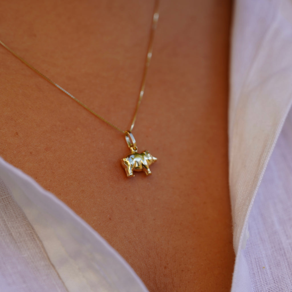 End view of the 14K Solid Gold Pig Charm worn by a model, highlighting the charm’s detailed craftsmanship and gold shine from a side angle.