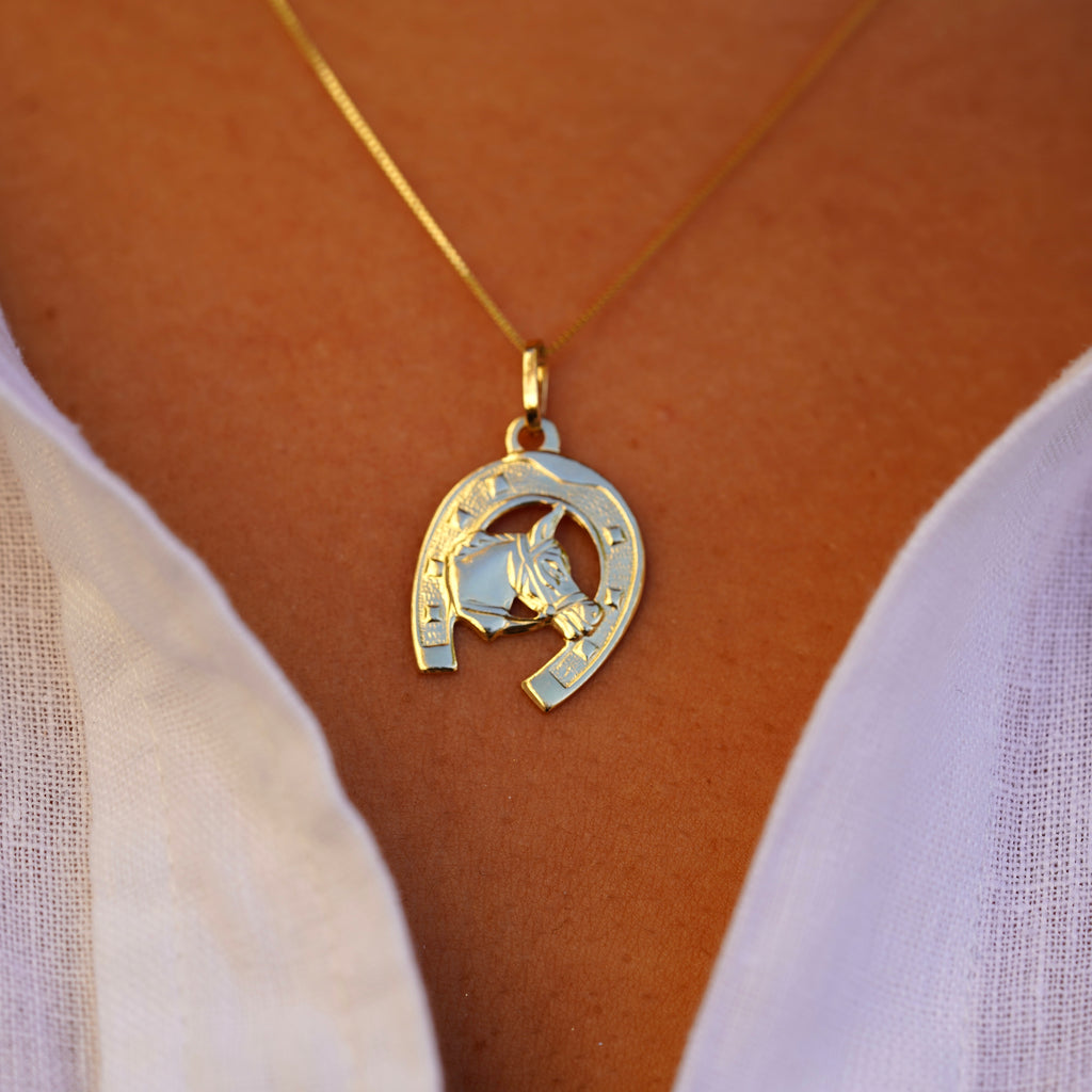 Close-up of a model wearing the 14K Solid Gold Horse with Horseshoe Pendant, highlighting the detailed design and polished gold finish.