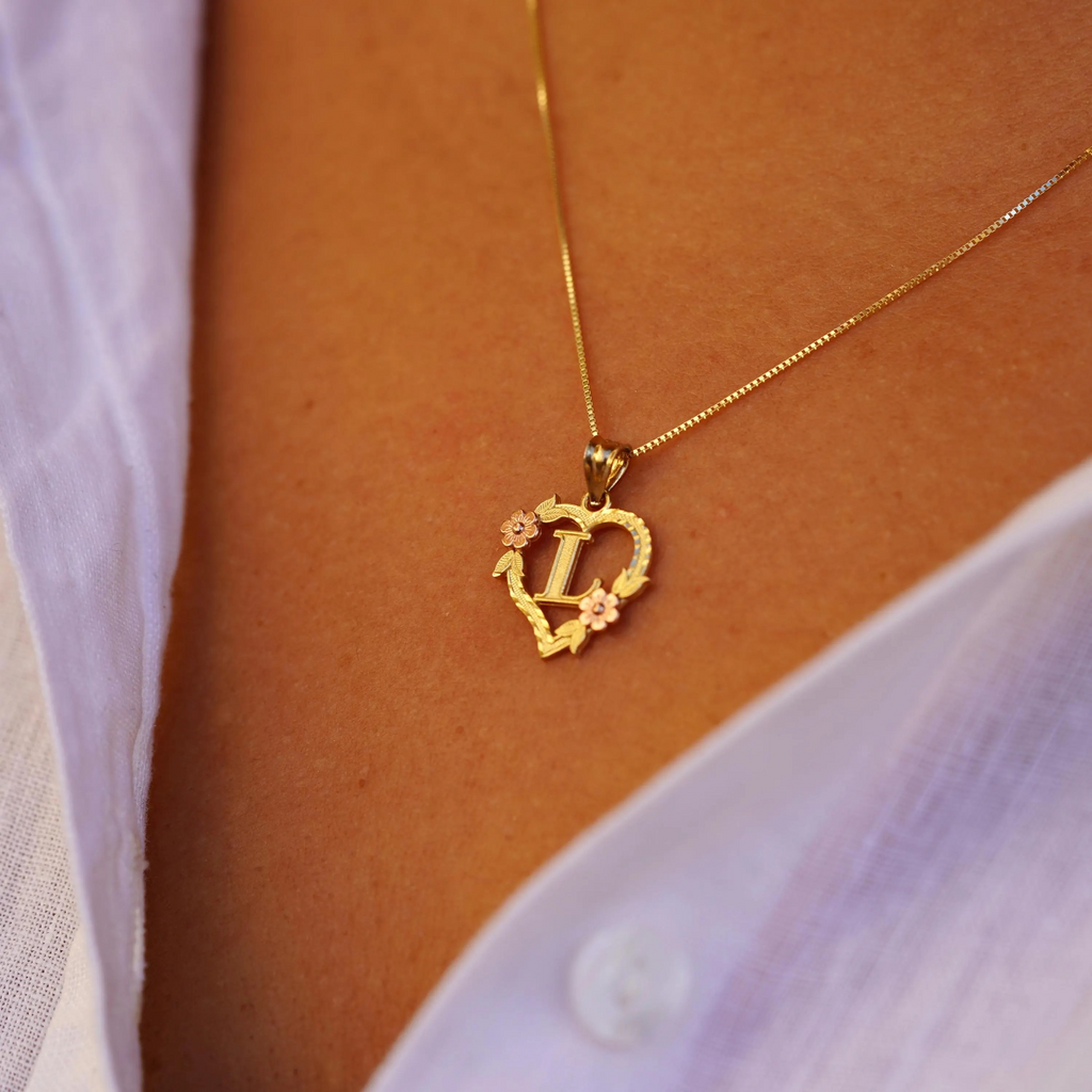 Model wearing the 14K Two-Tone Initial Heart Pendant with Letter L, showcasing the charm from the right side with a mix of yellow and rose gold.