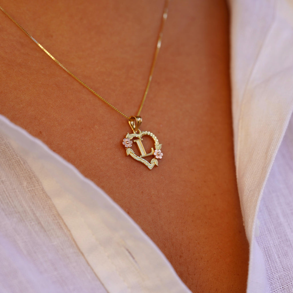 Model wearing the 14K Two-Tone Initial Heart Pendant with Letter L, highlighting the charm from the left side with elegant yellow and rose gold tones.