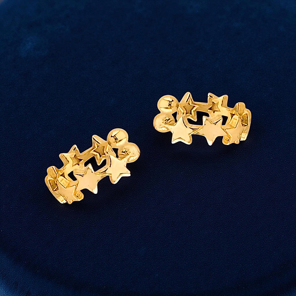 14K yellow gold star ear cuff resting on a dark blue cloth, showcasing its polished shine and minimalist star shape.
