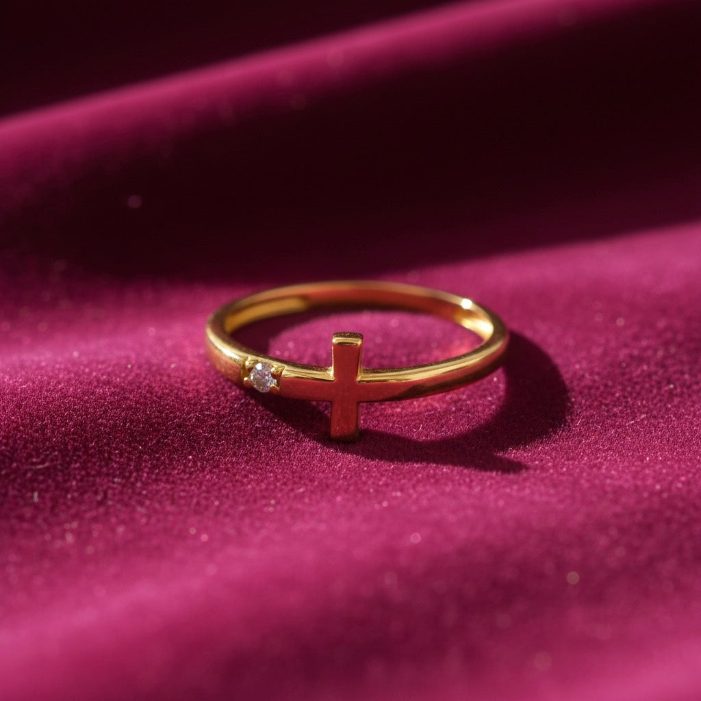 14K yellow gold CZ cross ring laid on rich magenta velvet, highlighting the bright CZ stones and warm gold shine against the soft textured fabric.