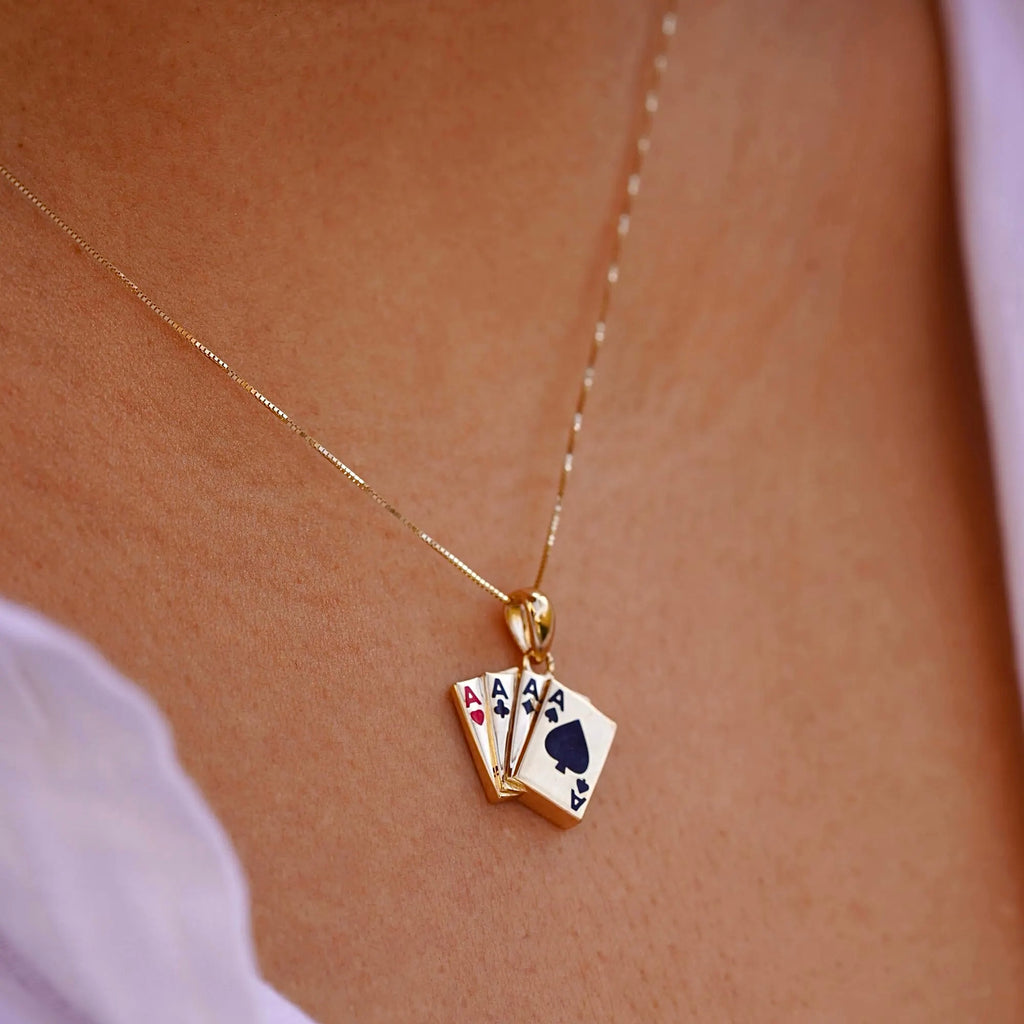 A model wearing the 14K Solid Gold 4 of a Kind Aces Charm on a fine gold chain, showcasing the pendant's elegant and playful design as it adds a touch of luck and style to her outfit. The charm is visible against a casual, everyday setting.