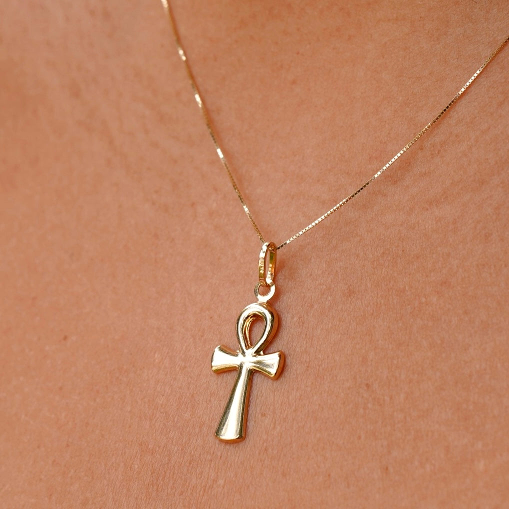 A stylish model wearing the 14K gold Ankh pendant on a fine chain, with the pendant elegantly positioned on their neckline, showcasing its delicate craftsmanship and cultural significance.