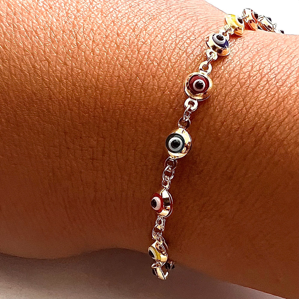 Model wearing a 14K gold mixed color evil eye bracelet on wrist, highlighting its colorful charms and delicate design as part of a stylish everyday jewelry look.