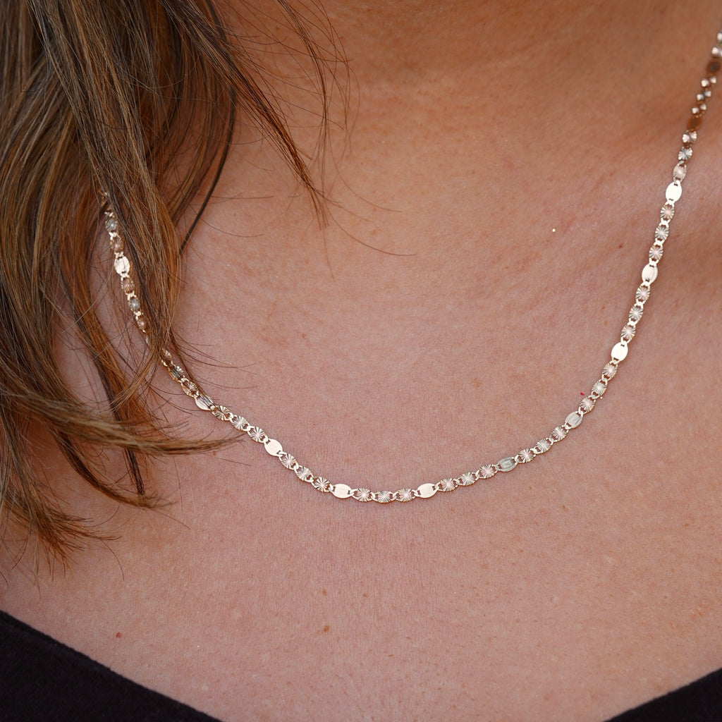 Model wearing the 14K tri-color 3mm Valentino Star Chain Necklace, showcasing its elegant shimmer and flat diamond-cut design against the skin.