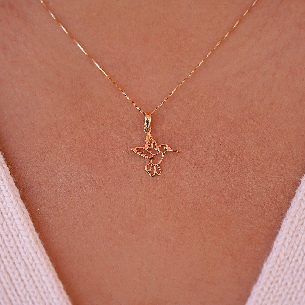 A model elegantly wears the 14K Yellow Gold Hummingbird Pendant on a delicate chain, highlighting its dainty size and the joyful charm it adds to her everyday style.