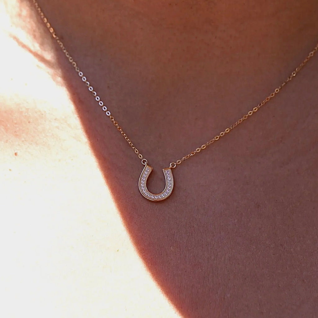 A model gracefully wears the 14K Solid Gold Horseshoe Necklace, showcasing its dainty and elegant design. The polished horseshoe pendant rests beautifully against the collarbone, adding a touch of luck and sophistication to any outfit. Perfect for layering or wearing alone as a meaningful statement piece.