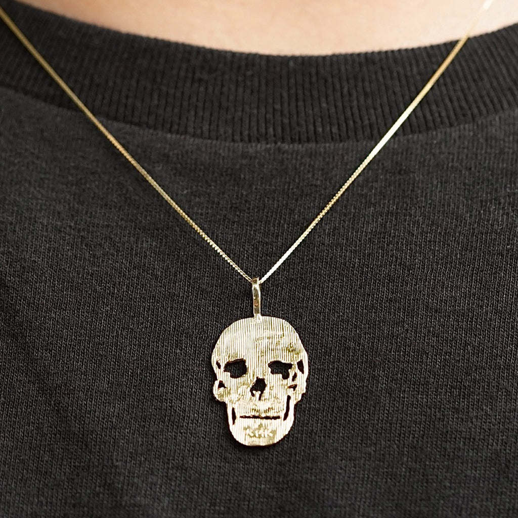 Model wearing a 14K Solid Gold Skull Charm on a gold chain, showcasing its bold and stylish appeal.
