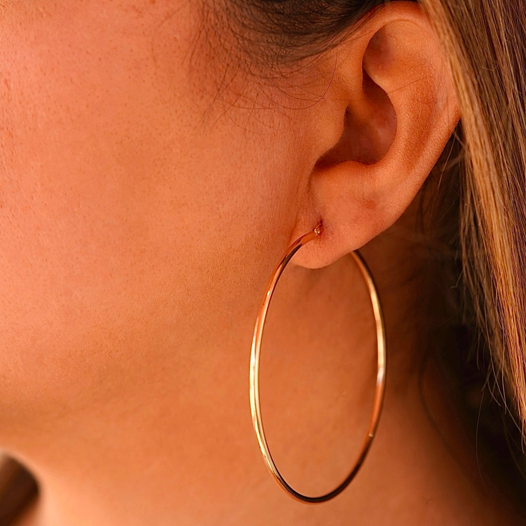 A woman wearing the 14K gold hoop earrings, highlighting their lightweight yet bold design, adding an elegant touch to her stylish outfit.