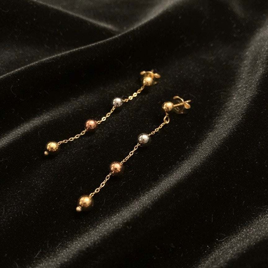 14K Tri-Color Gold Hanging Ball Earrings displayed on black velvet cloth, highlighting 3mm balls and 40mm drop in yellow, rose, and white gold.