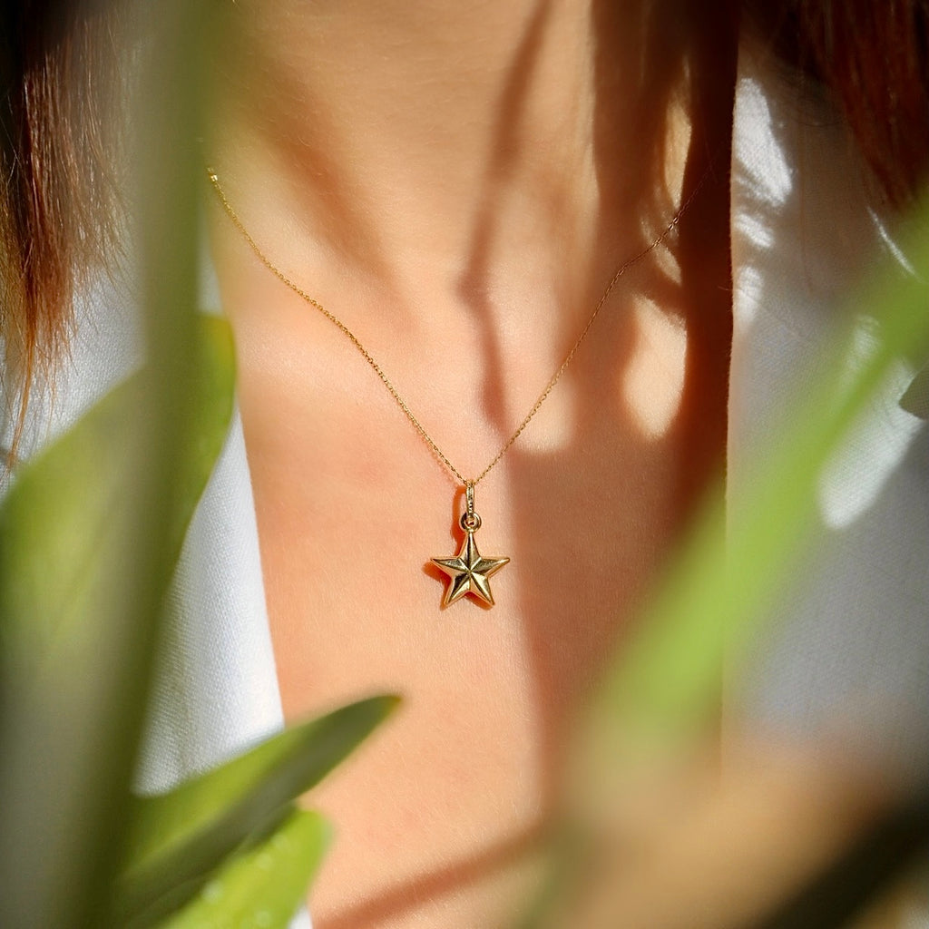 A stylish woman wearing the 14K solid gold starfish charm on a dainty chain, adding a subtle touch of ocean-inspired elegance to her summer outfit.
