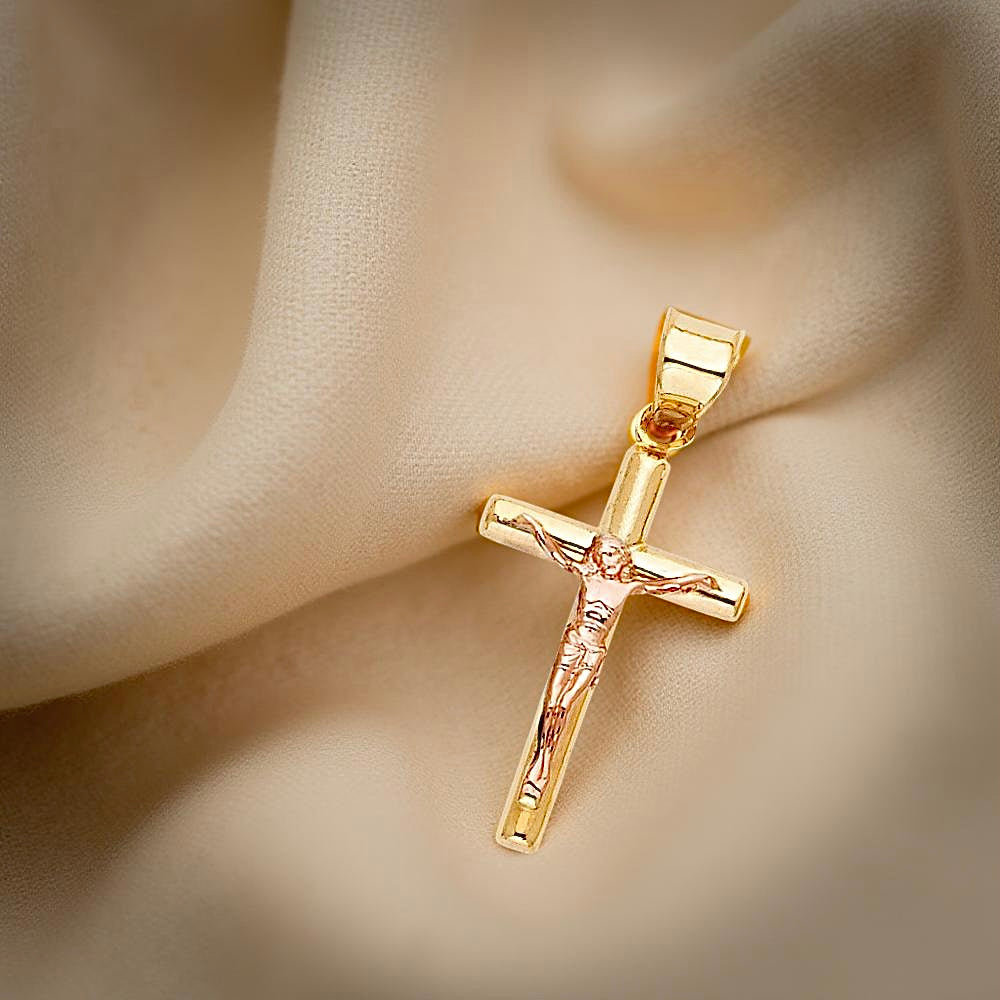 Close-up of a 14K two-tone crucifix pendant resting on a neutral textured fabric, highlighting the intricate figure of Christ and polished cross design.