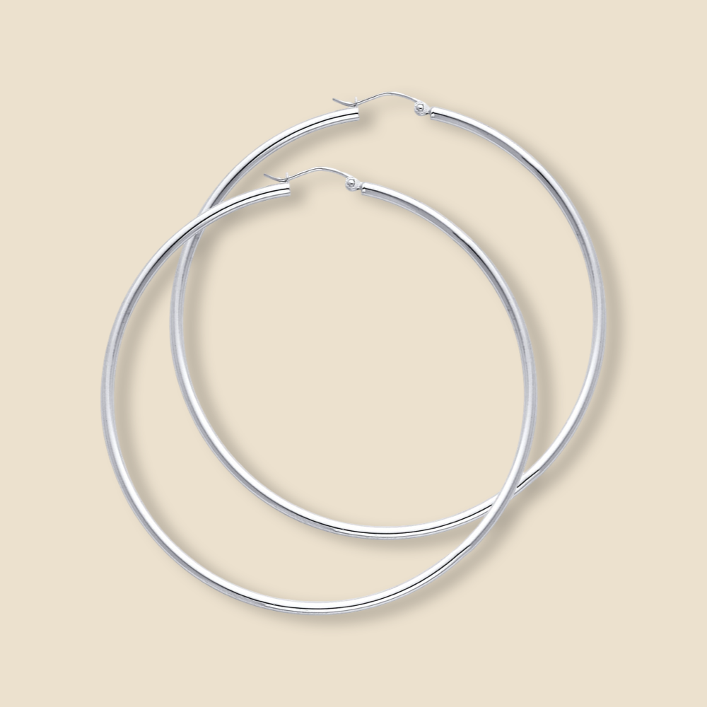 A pair of 14K white gold hoop earrings with a high-polish finish, displayed on a plain background, showcasing their smooth, round tube design and 65mm large size.
