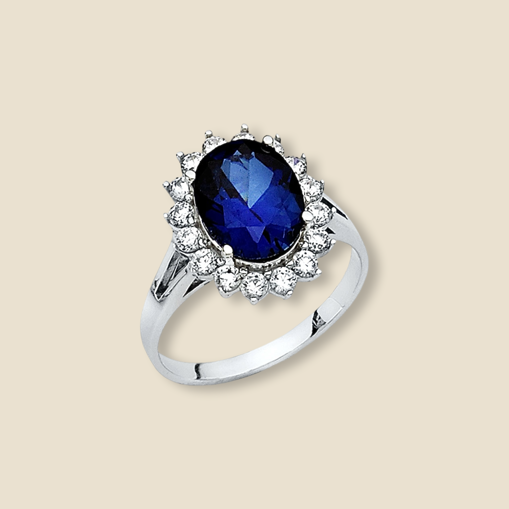 14K gold engagement ring with blue CZ stone photographed on a plain background, showcasing its white gold band and shimmering stone.