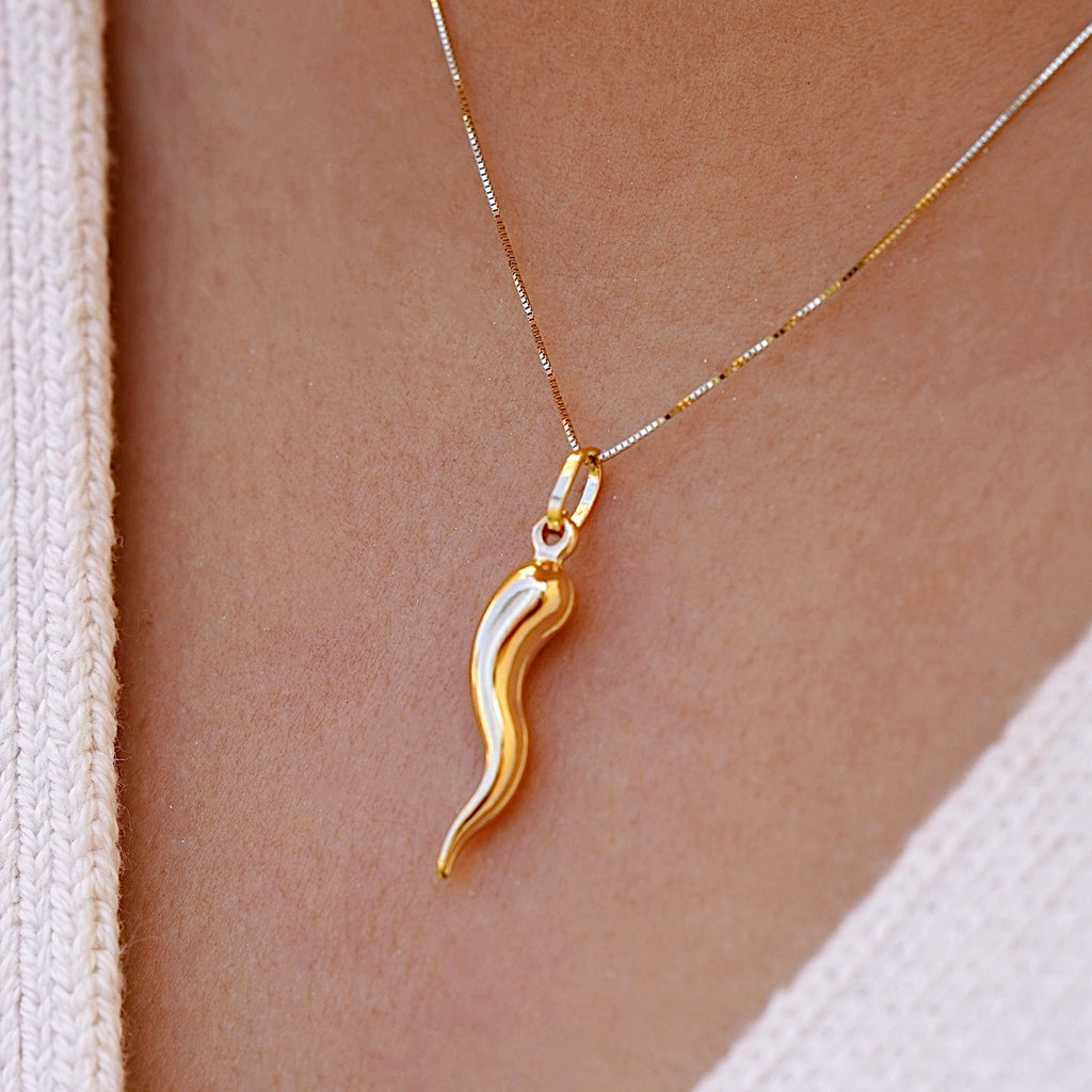 A model wears the 14K Yellow Gold Hollow Horn Pendant on a delicate chain, the pendant’s sleek, polished design resting gracefully on their chest. The hollow horn charm symbolizes protection and strength, adding a touch of elegance and spiritual significance to their look.