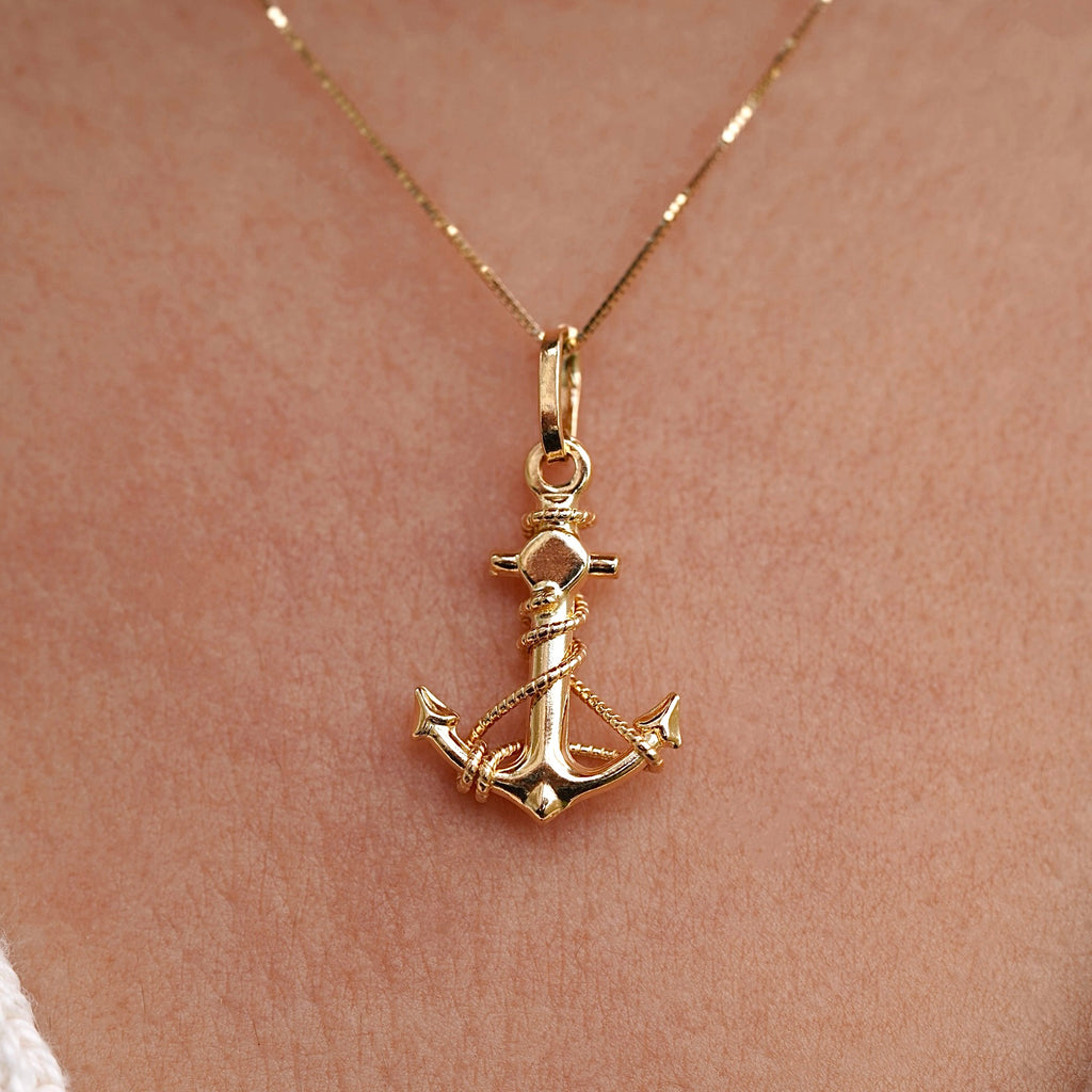 Model wearing a 14K gold anchor pendant on a delicate chain, showcasing the dainty nautical charm against the neckline for an elegant, maritime-inspired look.