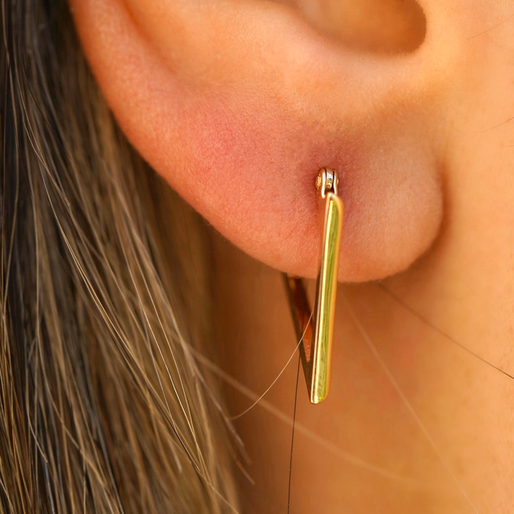 A stylish model wears the 14K Yellow Gold Triangle Hoop Earrings, with the dainty geometric hoops adding a modern, elegant touch to her everyday look.