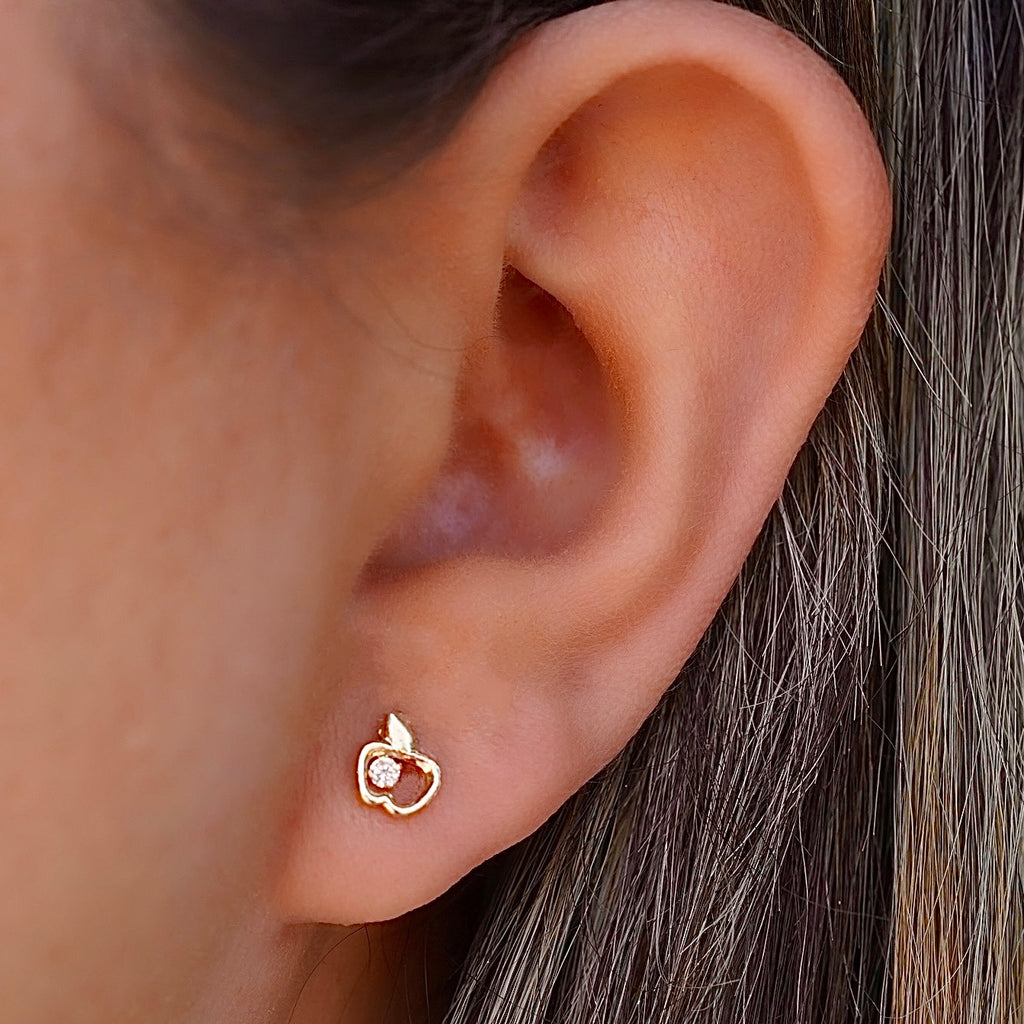 A close-up of a model wearing the 14K Gold Apple Stud Earrings, showcasing their dainty and minimalist design, adding a subtle sparkle to a casual yet chic outfit.