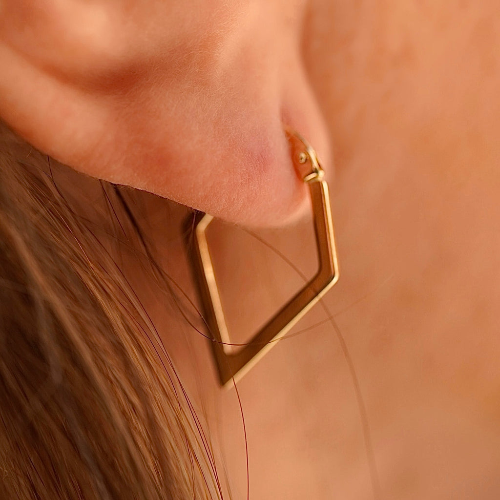 Model wearing 14K gold diamond shape hoop earrings, showcasing the lightweight, modern design and elegant drop length.