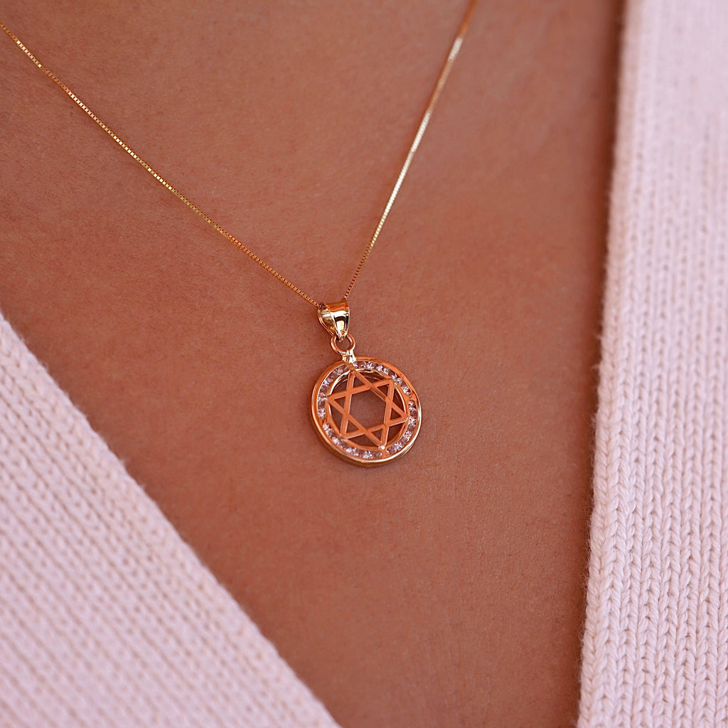 A model wearing the 14K gold Star of David pendant on a delicate gold chain, showcasing how the spiritual charm rests beautifully against the skin, with the CZ stones adding subtle sparkle.
