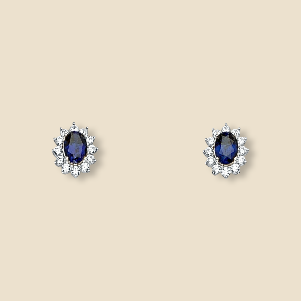 Close-up of 14K white gold blue CZ stud earrings on a plain background, showing their round shape and sparkling stones.