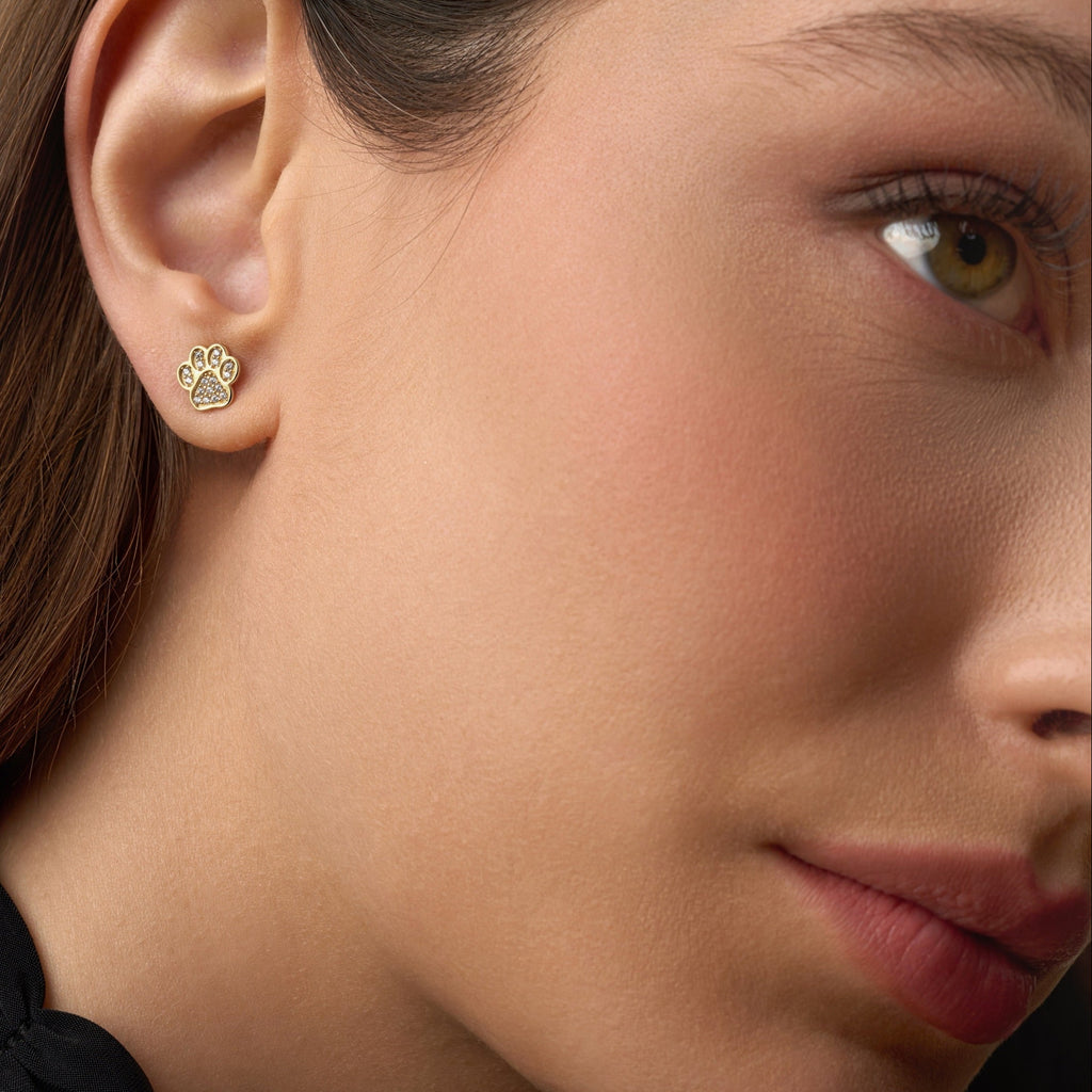 Model wearing 14K gold paw stud earrings featuring sparkling CZ stones, adding a delicate and meaningful touch to her everyday style.