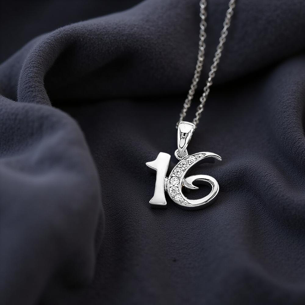 Elegant 14K white gold Sweet 16 charm pendant displayed on a black fabric, showcasing its polished finish and delicate craftsmanship in a warm, natural light setting.
