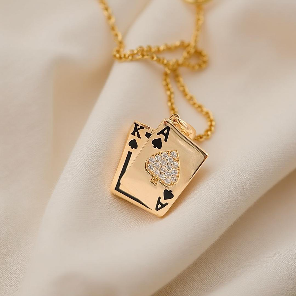 14K gold CZ Spade A & K card pendant resting on textured off-white fabric background, showcasing sparkling details.