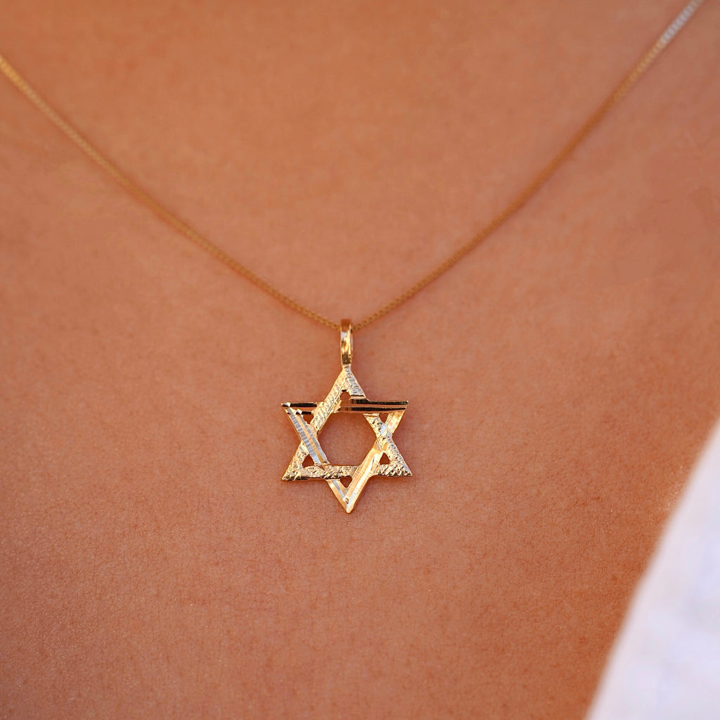 A model wearing the 14K Gold Star of David Pendant on a delicate gold chain, with the pendant resting near their collarbone, adding a subtle touch of faith and elegance to their look.