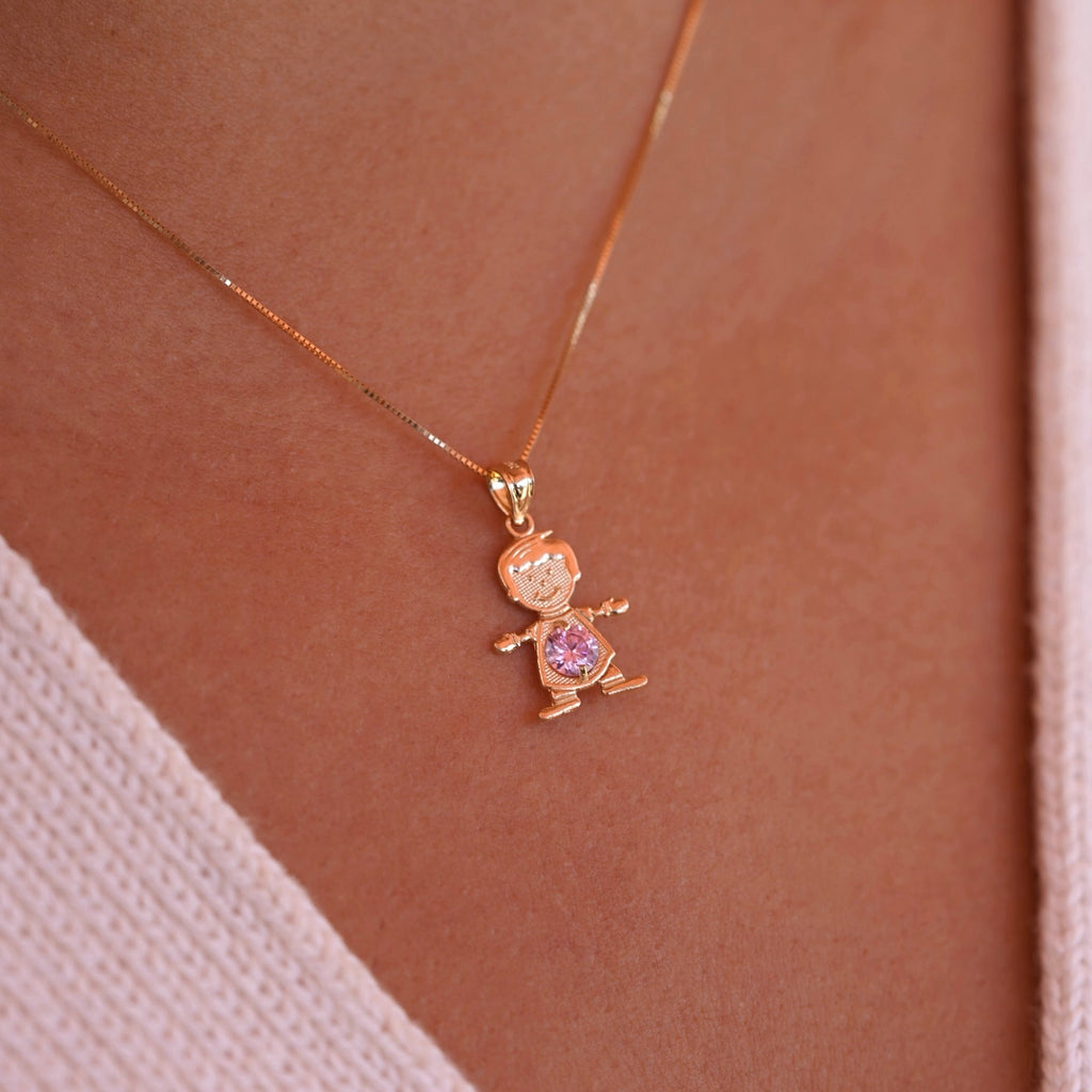 A model wearing the October birthstone boy charm on a delicate gold chain, showing how the 14K gold pendant sits lightly near the collarbone with the pink CZ sparkling subtly in the light.
