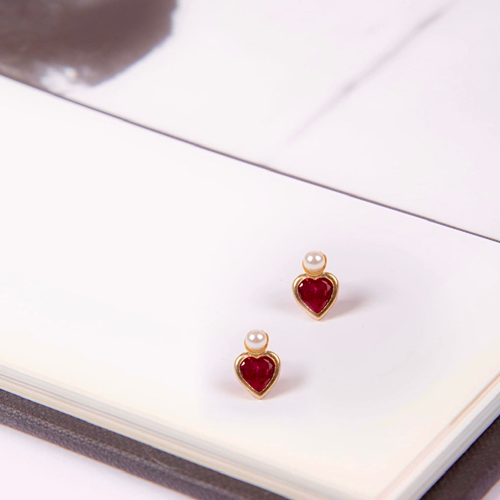 A close-up image of the 14K Gold Heart CZ & Pearl Earrings against a plain white background, showcasing their delicate heart-shaped cubic zirconia and luminous pearl set in polished yellow gold.