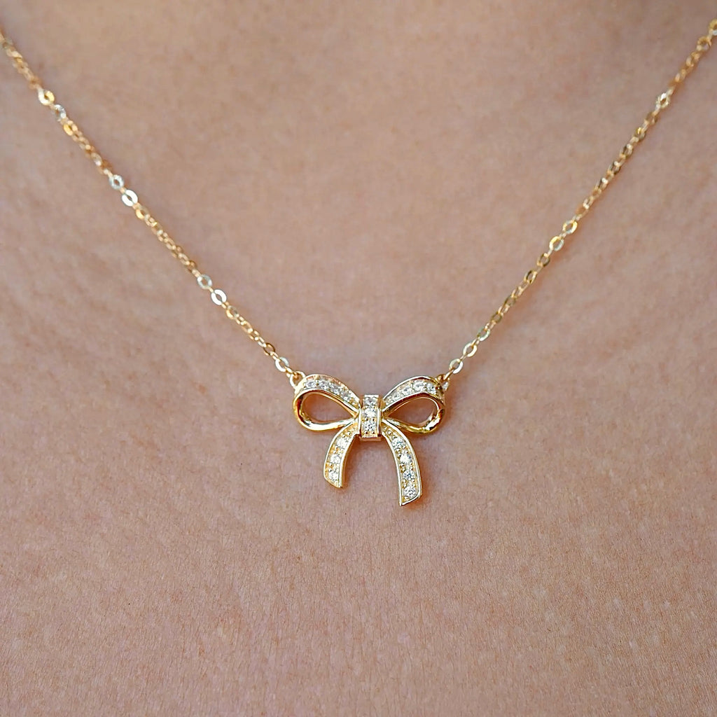 Model wearing the 14K gold ribbon necklace, capturing its dainty charm and graceful fit around the neckline.