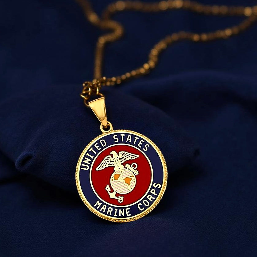 High-resolution close-up of a 14K Yellow Gold US Marine Corps pendant resting on navy blue fabric, highlighting the detailed emblem and craftsmanship.