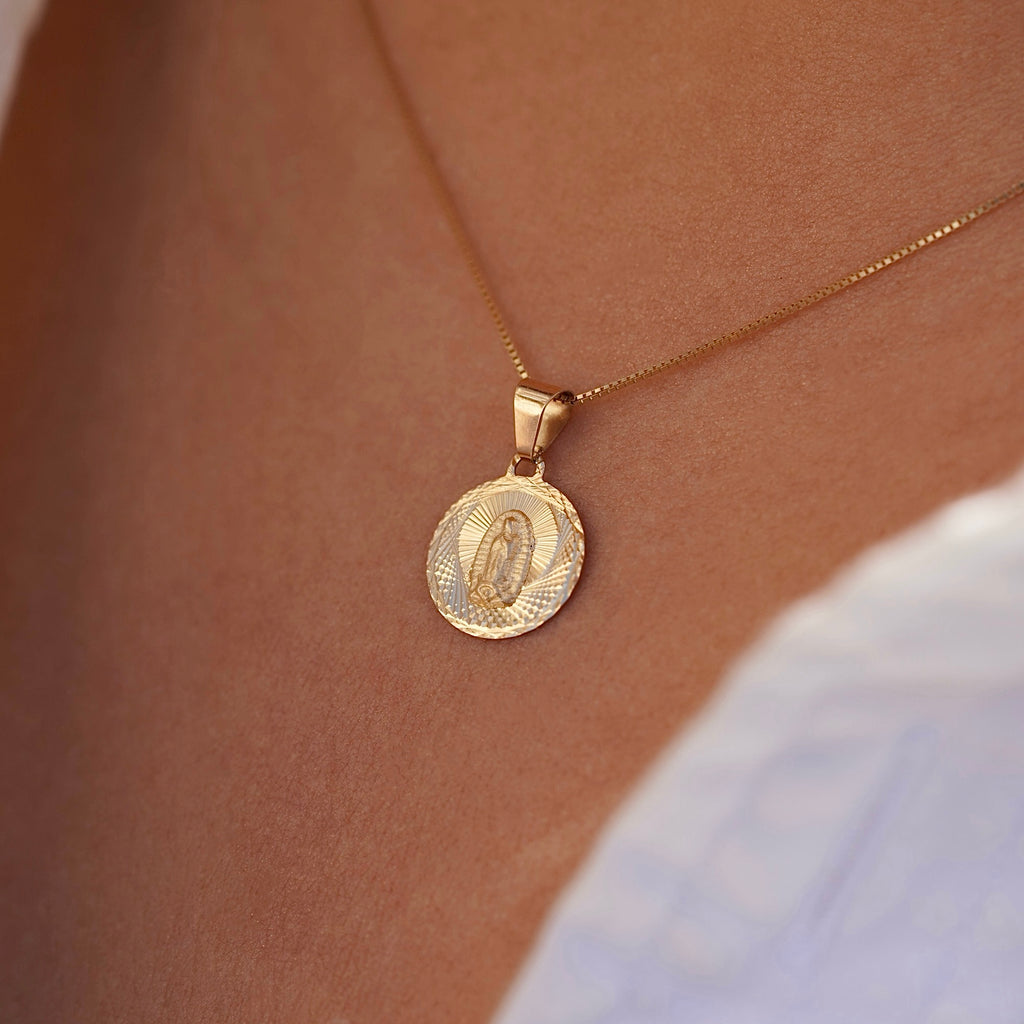 A model wears the 14K gold religious stamp pendant on a fine chain, the charm resting gently near the collarbone, blending timeless faith with everyday elegance.