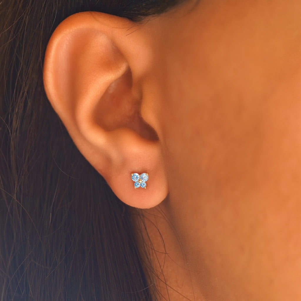 A model wearing 14K yellow gold butterfly CZ screw-back stud earrings, showcasing their delicate size and sparkling blue cubic zirconia accents for a chic everyday style.
