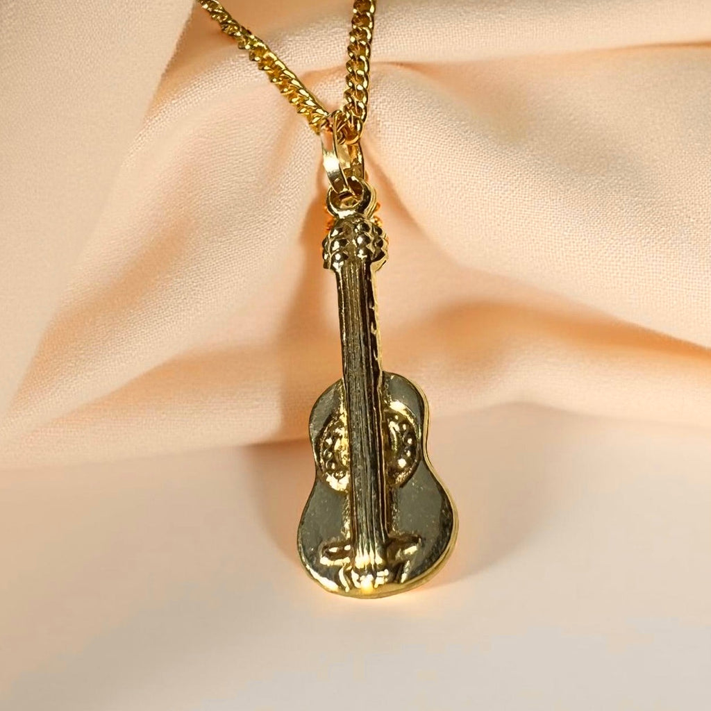 14K Gold Cello Pendant displayed on a textured, off-pink linen cloth, highlighting its polished shine and delicate string details.