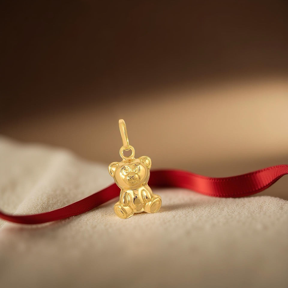 14K Gold Teddy Bear Charm Pendant displayed on a cream-colored velvet, highlighting its delicate details and warm golden glow.