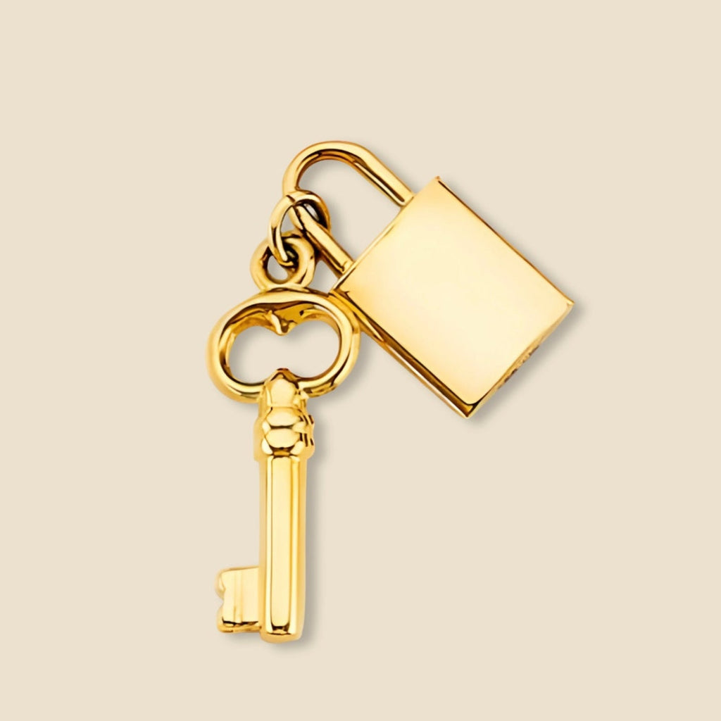 Studio shot of a 14K yellow gold lock and key charm pendant photographed on a plain background, highlighting the fine details, warm gold tone, and meaningful romantic design.