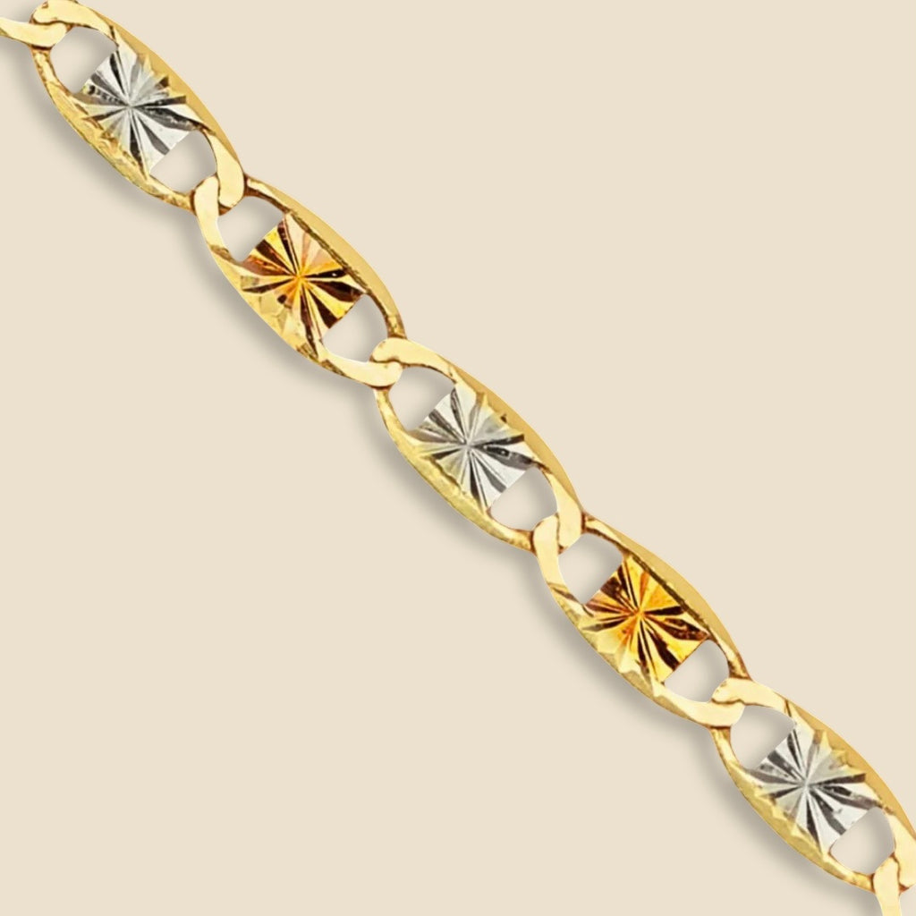 A close-up of a 14K tri-color Valentino chain laid on a plain background, showcasing its intricate links in rose, white, and yellow gold.