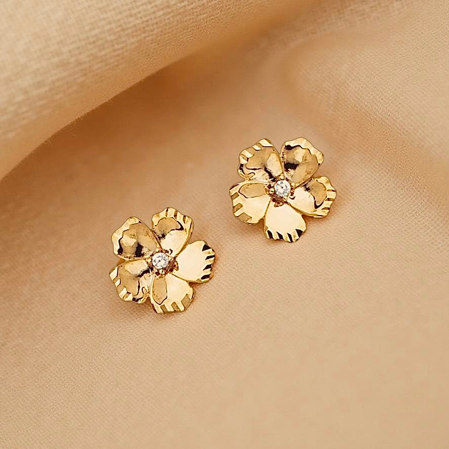 14K gold flower pendant earrings with sparkling CZ, elegantly resting on a textured neutral cloth background.