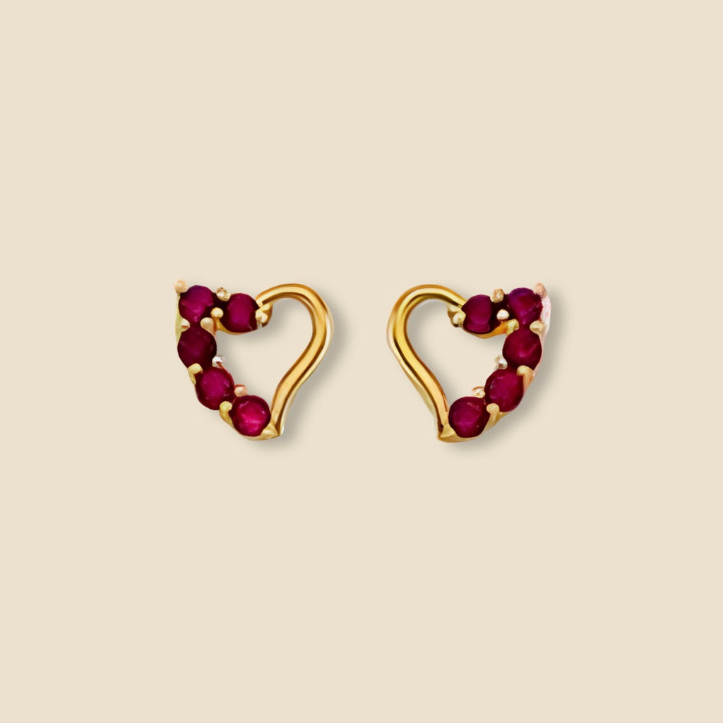 Close-up of 14K Yellow Gold Heart Pendant with Red CZ stone on a plain background, highlighting fine craftsmanship.