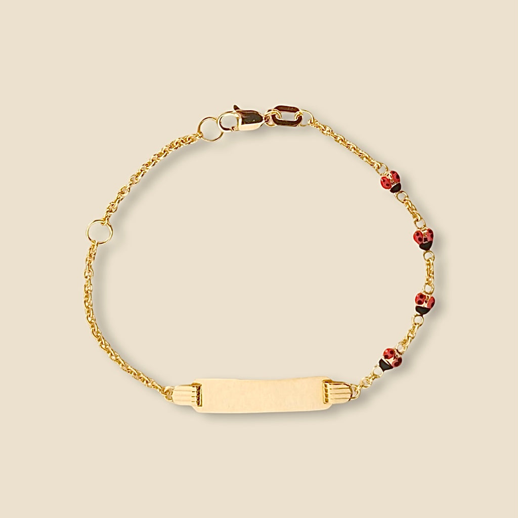 14k yellow gold baby id bracelet with red ladybug charm and engravable plate displayed clearly on a plain background, highlighting its polished finish and delicate size.