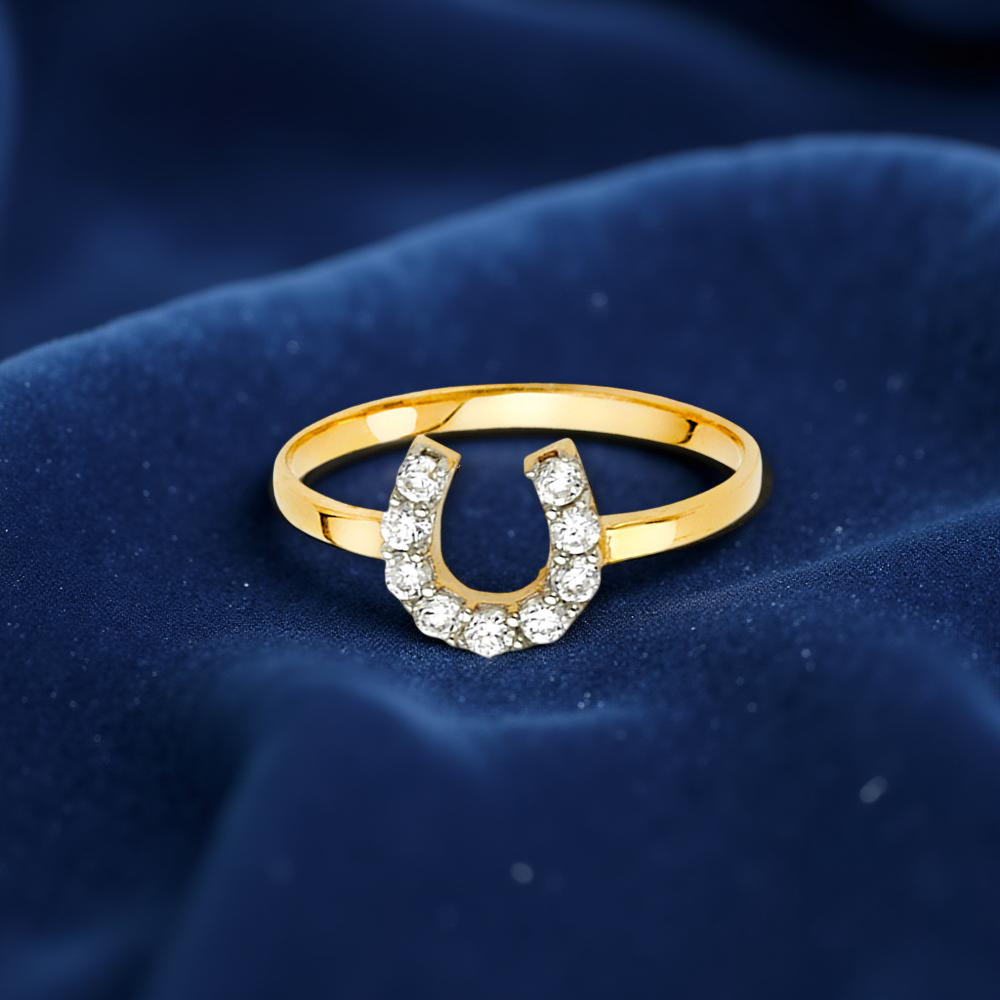 14K two-tone gold fancy ring with CZ accents resting on dark blue velvet fabric, highlighting its shine and texture.
