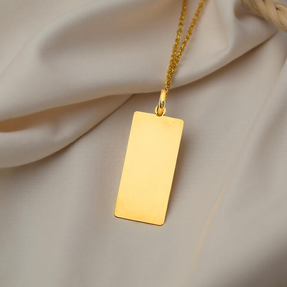 14K yellow gold engravable bar pendant resting on a soft off-white fabric background.
